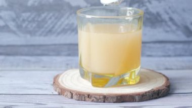 pouring white sugar in a glass of Juice on table ,