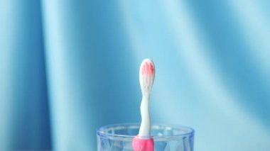  slow motion of colorful toothbrushes drops in a glass .