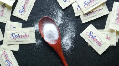 Siyah arka planda bir kaşık beyaz tatlandırıcı 