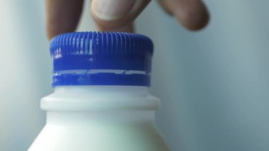 slow motion of open a cap of a milk container .