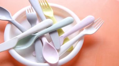 Masada renkli plastik tabaklar, cam ve çatal bıçak takımı .