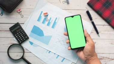 holding smart phone and analyzing financial data .