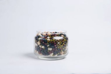 mixed beans in a glass jar on white .