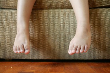 close up of 5 years old child dry feet sitting on sofa .
