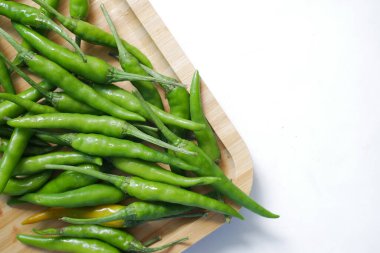close up of green chili on a chopping board on white background .