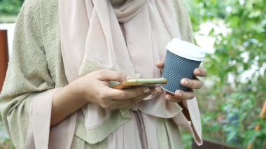  Kadınlar ellerinde akıllı telefon ve kağıt kahve fincanı tutuyorlar. ,