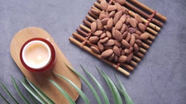 herbal cream cosmetic in a container and almond nut on table ,