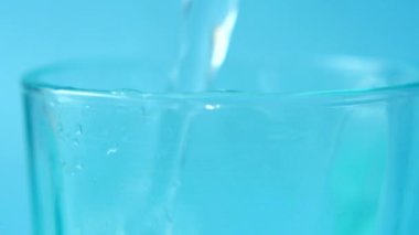 detail shot of pouring soft drinks in a blue color glass .
