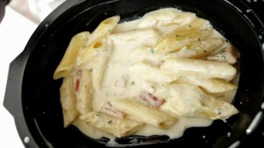 women eating cream pasta on a plastic take away packet .