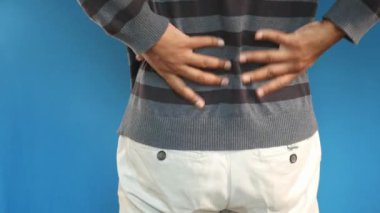 Sırt ağrısı çeken mavi gömlekli genç adam.