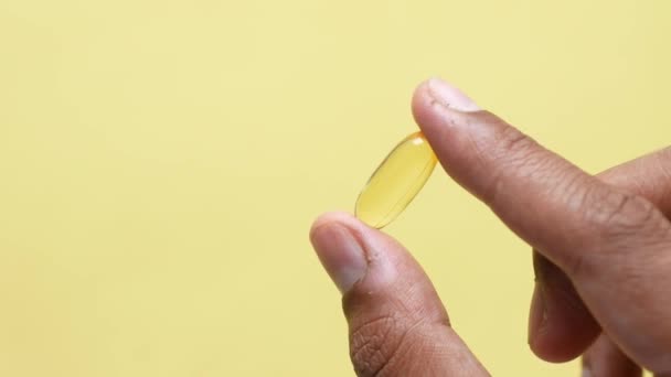 Holding Fish Oil Supplement Yellow Background — 图库视频影像