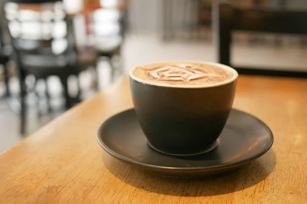 a cup of late coffee with flower shape design on top at cafe .