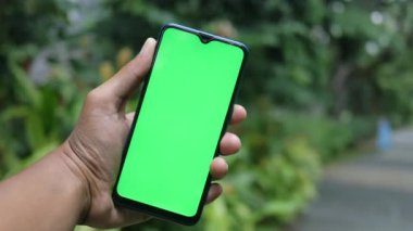 Açık havada akıllı telefon kullanan genç bir adamın dikiz görüntüsü .