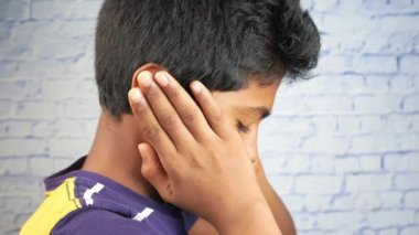 teenage boy having ear pain touching his painful ear 