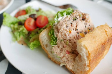 Ton balıklı sandviç ve masada taze salata. 