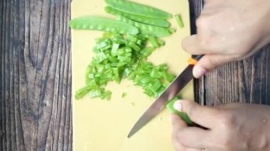women cutting Holland beans on the cutting board.