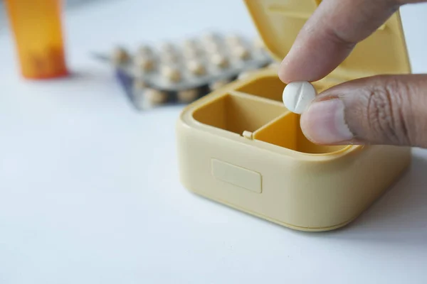 mans hands taking medicine from a pill box .