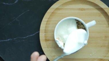  putting yogurt in granola Musli in a bowl