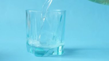 Mavi arka planda bir bardağa alkolsüz içecekler dolduruyorum. ,