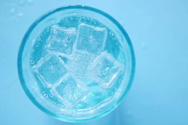 soft drinks in a glass with ice cube on blue background .
