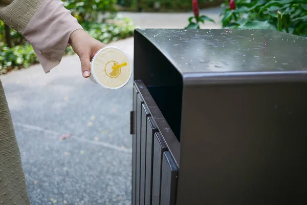 women hand throwing an empty plastic water bottle in the garbage trash or bin,