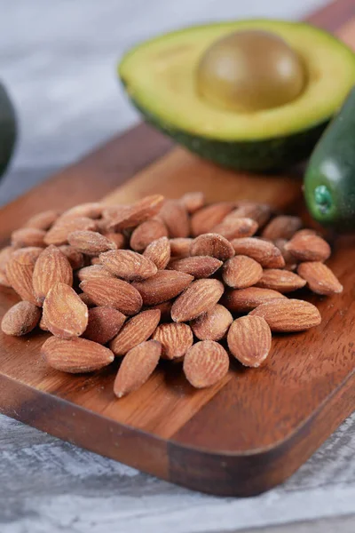 close up of slice of avocado and almond nut on chopping board.,