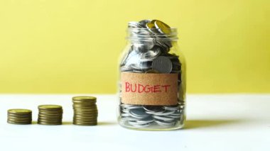 budget text on a saving coins jar on white ,
