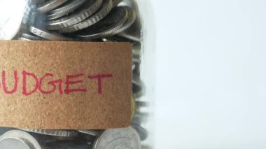 budget text on a saving coins jar on white ,