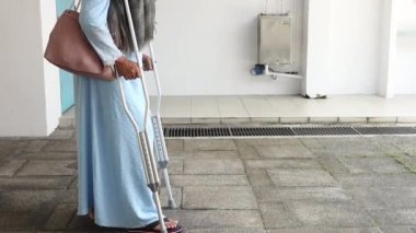 Koltuk değnekleriyle kırık bacaklı genç kadınlar.