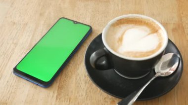 yeşil ekran ve kahve fincanı olan akıllı telefon. ,