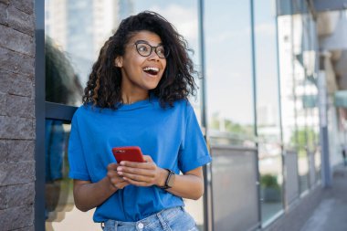 Genç Afrikalı kadın internetten cep telefonu alışverişini başka tarafa bakarak yapıyor. Ağzı açık, sokaklarda oyun oynayan mutlu bir kadın, kopyalama uzayı. İlham, Kara Cuma konsepti  