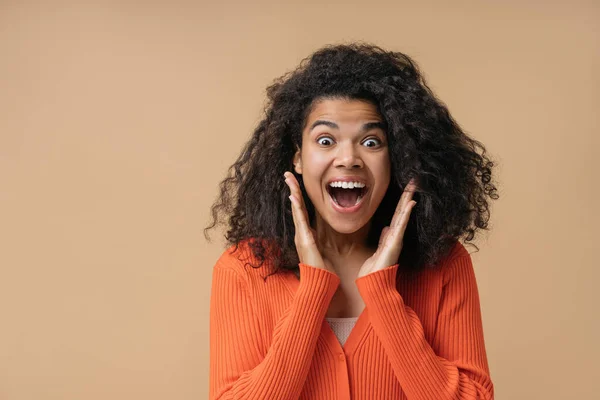 Young surprised African American woman holding hands near face screaming, celebration success looking at camera. Portrait of funny overjoyed female with open mouth isolated on background
