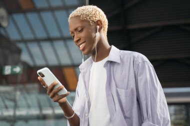 Genç, gülümseyen, şık saçlı, cep telefonlu mesaj okuyan, sokakta iletişim kuran Afro-Amerikan bir adam. Mobil uygulama kullanan hippi açık havada müzik dinliyor. 