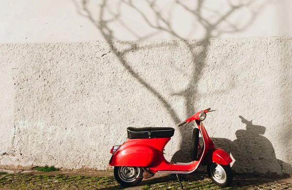 Red Scooter Vespa Parked on the Road Street with Tree shadows