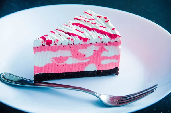 Mutlu yıllar dilimlenmiş beyaz ve pembe kremalı pasta beyaz tabakta gümüş renkli çatalla