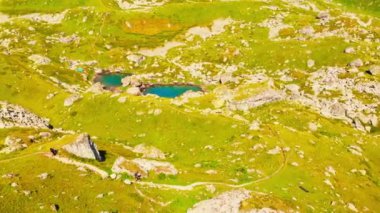 Yürüyüş parkurundaki iki yürüyüşçü doğa manzaralı yeşil dağlarda eğleniyor. Kazbegi ulusal park keşfi. Gürcistan gezisi.