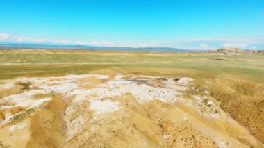 Gökyüzü turistleri Chachuna doğa koruma alanındaki çamur yanardağlarını araştırıyor. Güneşli bir günde yeşil alan arkaplanı olan Kakheti, Georgia.
