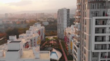 Tiflis, Gürcistan - 17 Ekim 2021: Güneşli günbatımı arka planına sahip yeşil elmas apartmanlar kompleks binalar. Georgia emlak sektörü iş sektörü kavramı
