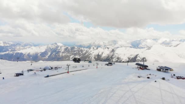 スローモーション映画的な空中ビューコーカサス山脈を背景にグダウリスキー場のスキー場 — ストック動画