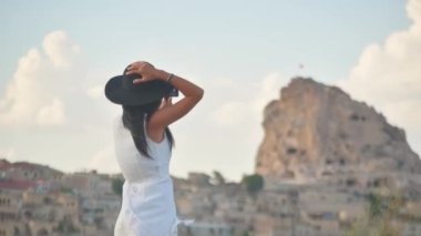 Sabit görüşlü, beyaz elbiseli, akıllı telefonlu, el kameralı genç bir turist. Manzaralı bir yerde tatilleri yakalıyor.