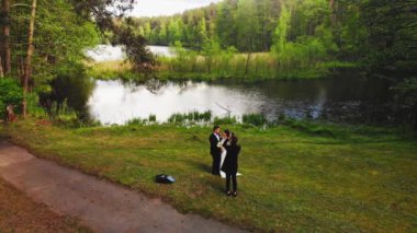 Kendini adamış profesyonel erkek fotoğrafçı doğada çekim yapıyor genç beyaz göl manzaralı düğün çifti