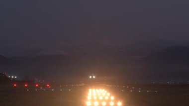Statik manzara Batumi havaalanı pisti ticari uçak kalkışı ve Kafkasya dağları arka planında. Gece yolculuğu konsepti. Uçak yerden kalkıyor.