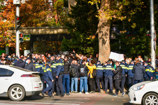 Tbilisi, Georgia - 10th november, 2021: Police officers surround crowd of aggressive protestors in street in public anti-government protest