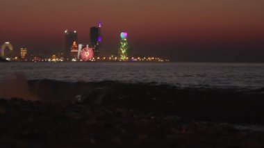 Gece şehri Batumi, turuncu alacakaranlık gökyüzü ve deniz manzaralı mavi saat. Batumi, Adjara, Georgia. Sunset 'teki Aydınlanmış Tatil Köyü Panoraması. Karadeniz; Dönme dolap ve Alfabe Kulesi