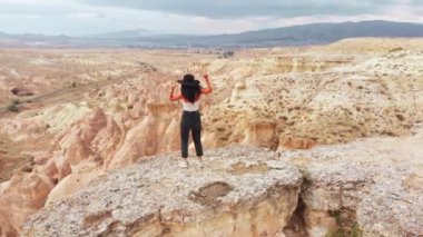 Genç, mutlu, güzel, beyaz kadın turist dansı ve kahkahaları açık havada kayalıklarda dans ederken eğleniyor. İyi tatiller. Dünyayı keşfet.