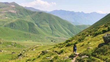Back view female hiker walk down trail hiking outdoors in Kazbegi national park, Georgia. Way to Roshka from Abudelauri lakes