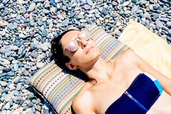 ダウンアップビューの女性日光浴で青ビキニで毛布で岩のビーチ — ストック写真