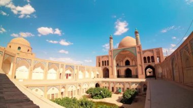 Kashan, İran - 29 Mayıs 2022: Turistler ve hacılar güneşli bir günde güzel Ağa Bozorg Camii 'nin zaman çizelgesini keşfedip etkileşime geçtiler