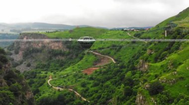 : Gürcistan kırsalındaki Dashbashi vadisinde cam köprü üzerindeki Elmas şekilli platformun üzerinde uçan hava aracı. Kafkasya 'daki vadi üzerindeki ünlü modern köprü