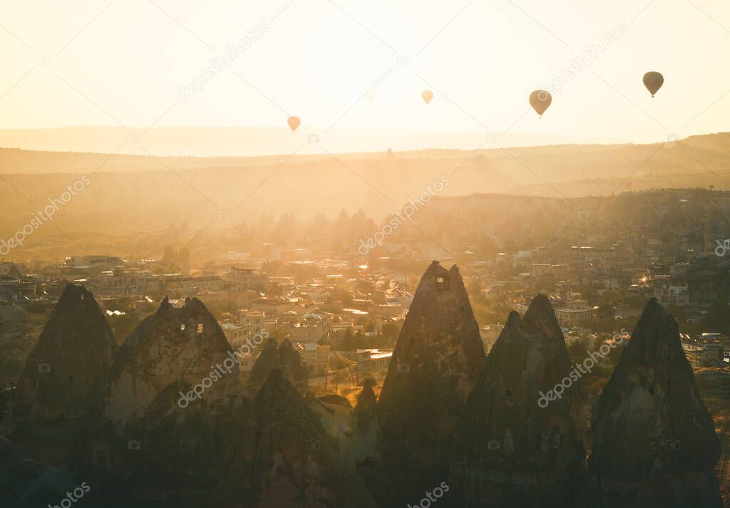 Golden sunrise over Goreme town in Cappaocia front side sunlight directional with balloons on air in sunny hazy autumn calm morning